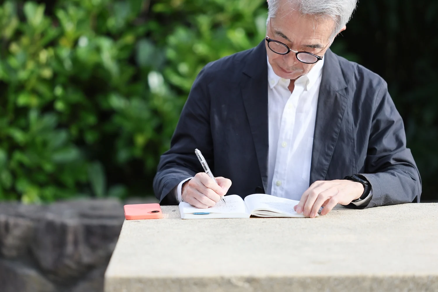 屋外のテーブルでノートを書くタイヨシフミ
